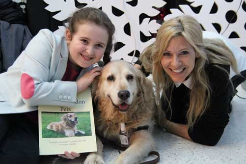 Evelina London patient, Amelie, Nala the dog and CBBC presenter Naomi Wilkinson pose with the Evelina London Pet Book
