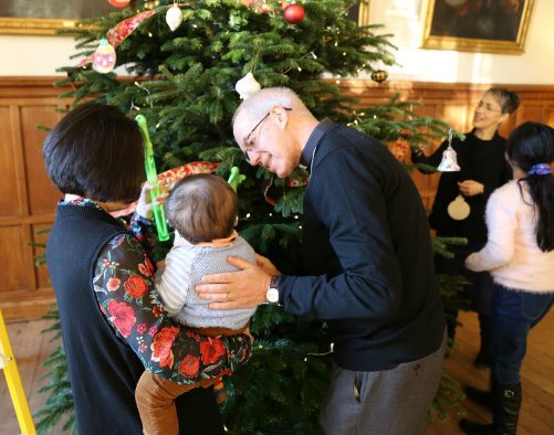 The Archbishop of Canterbury, Justin Welby, with a family next to a large Christmas tree in Lambeth Palace