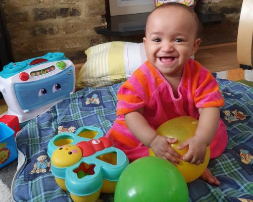 Baby Sayanna celebrating her birthday with balloons and toys.