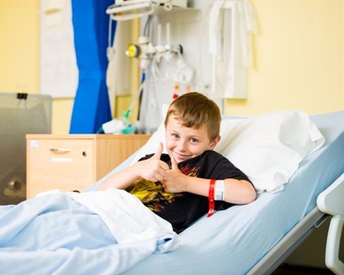 Boy giving thumbs up in hospital bed