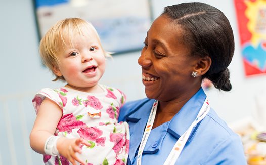 Nurse holding little girl, both smiling