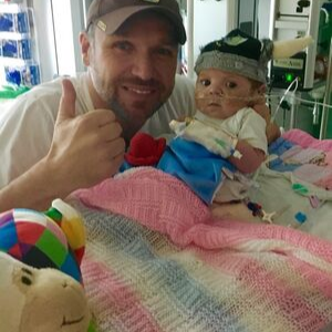 Baby Evalina Cox in a cot at the hospital with her dad.