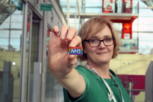 Dr Anne Gordon holding a NHS Rainbow Badge