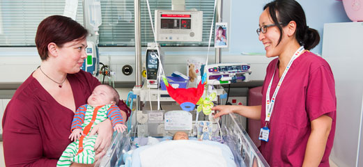 Nurse talks to mum at cot