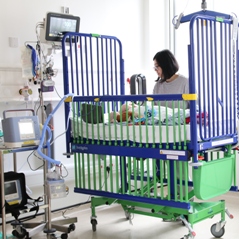 Parent with baby in cot on Snow Leopard Ward